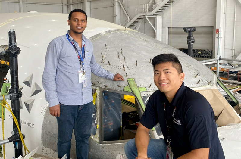 Two employees working on aircraft exterior.